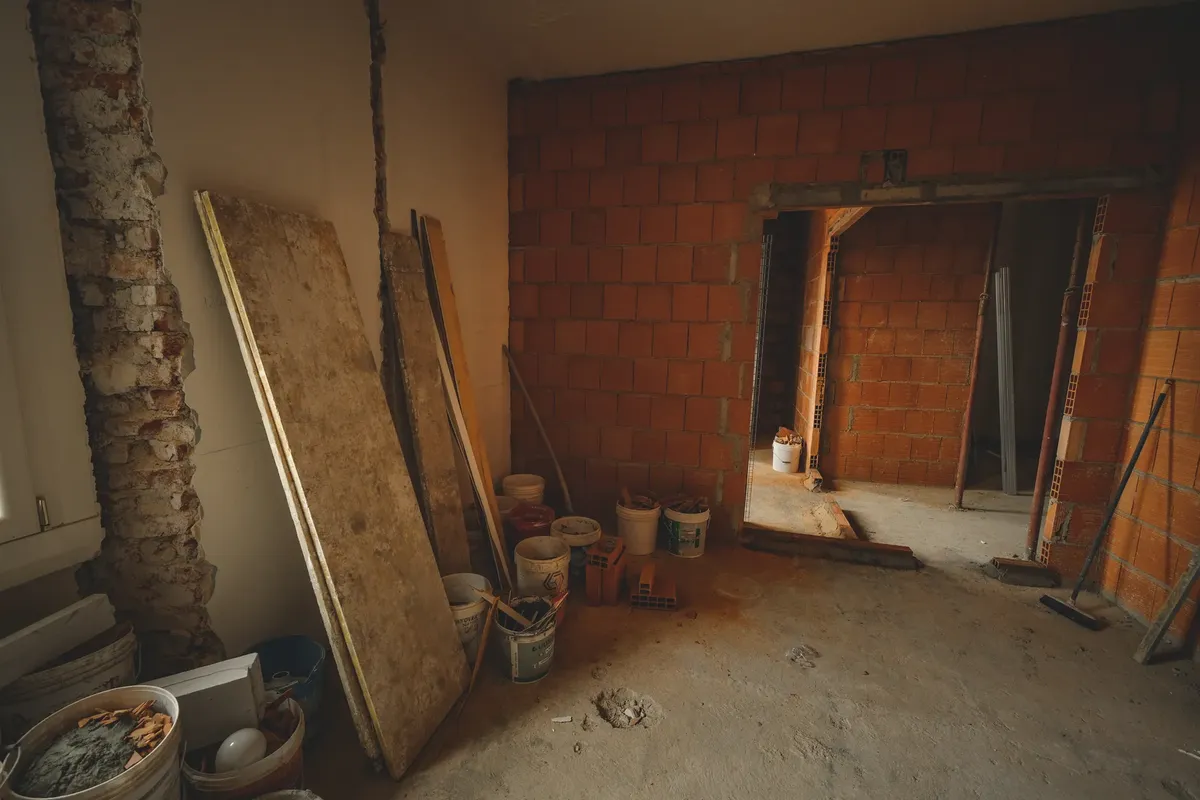 A red brick wall under construction with tools and materials scattered around in a renovation project.