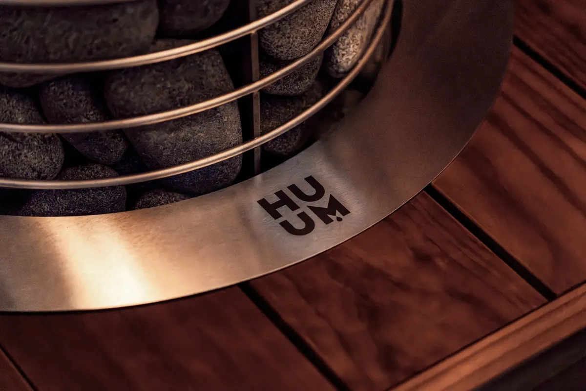 Close-up of a modern electric sauna heater with stones and wooden details in a stylish indoor setting.