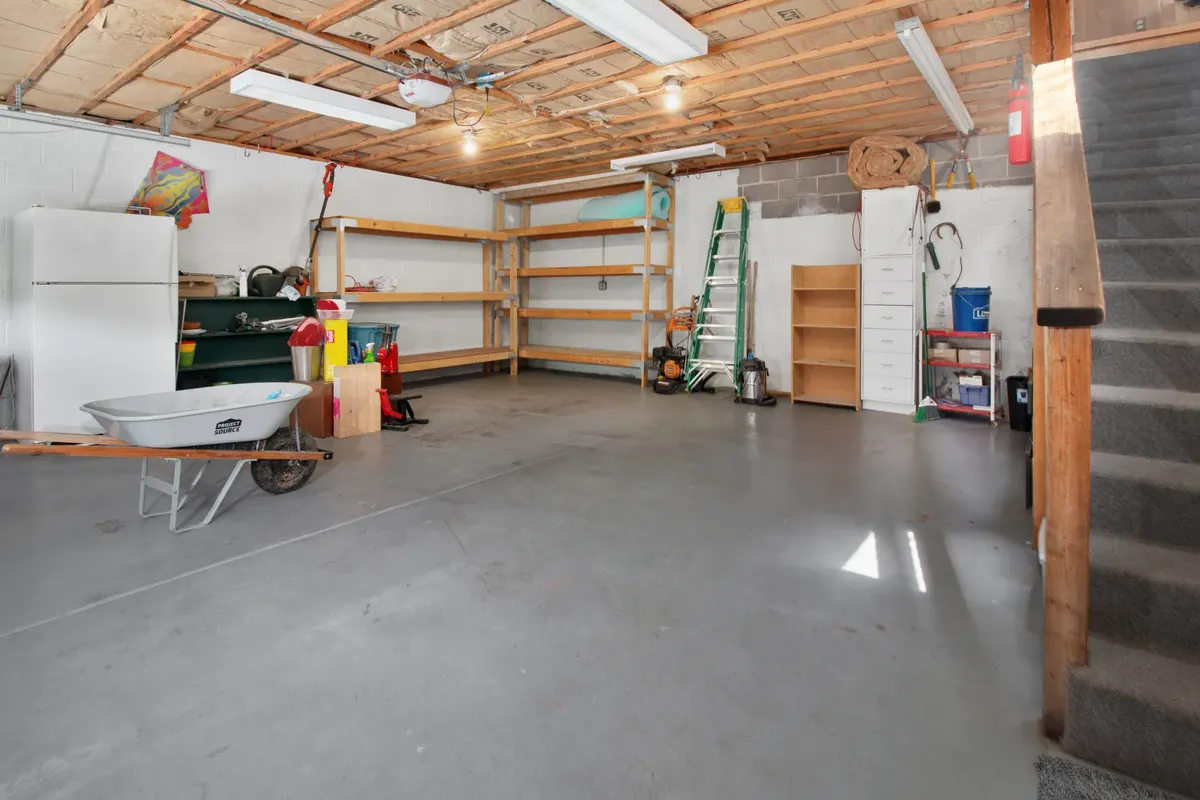 Spacious garage interior with storage shelves, tools, and a wheelbarrow, ideal for home organization.