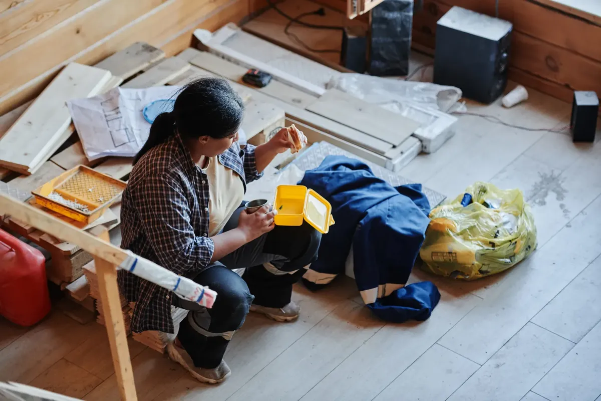 A female construction worker taking a lunch break in a house under renovation, viewed from above.
