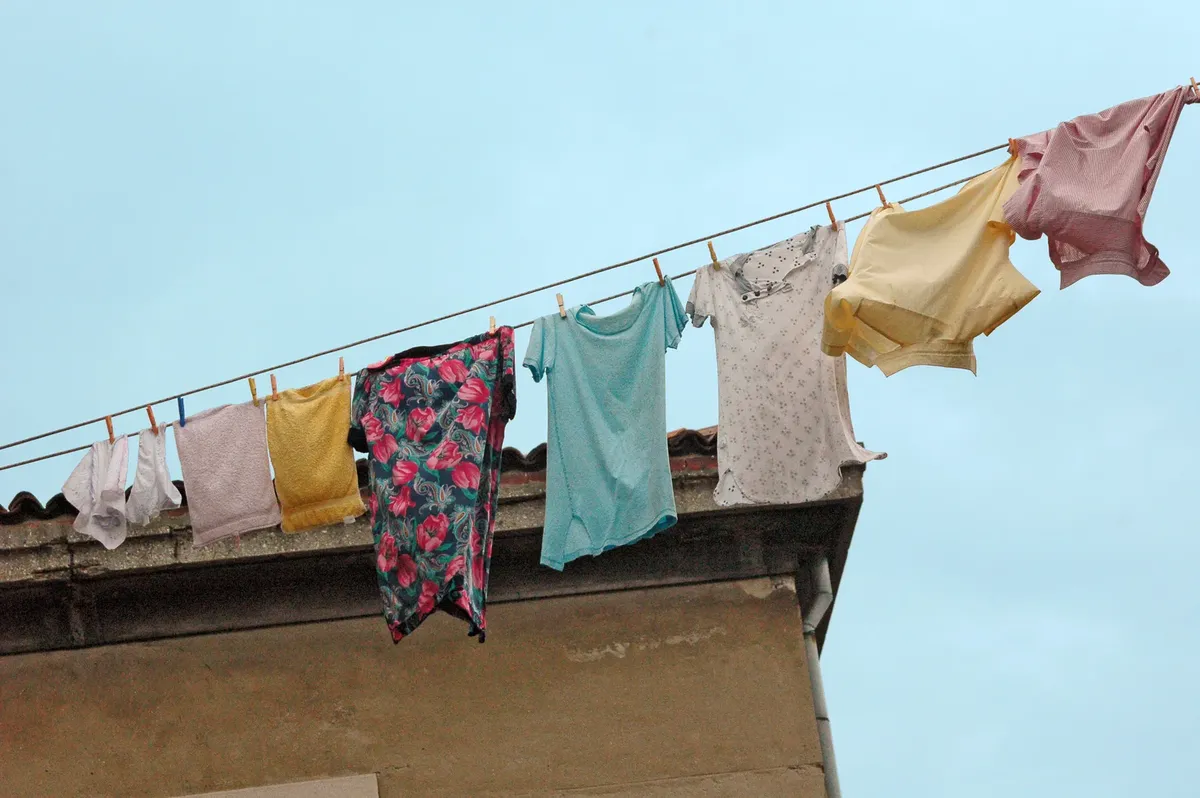 Vibrant clothes drying on a rooftop clothesline against a blue sky.